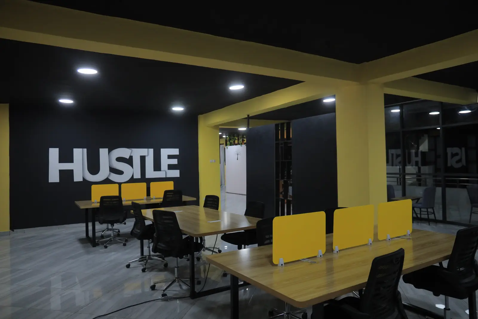 The co-working floor at Ethio CS Hub, with yellow desk dividers and the HUSTLE wall