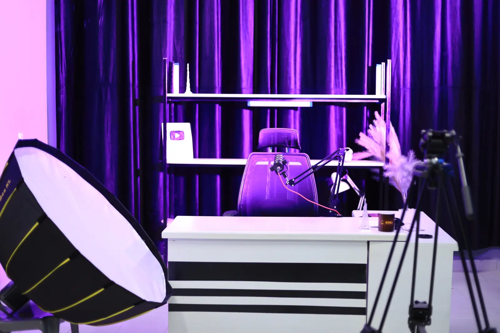 The production studio lit in purple, with a desk, microphone and softbox